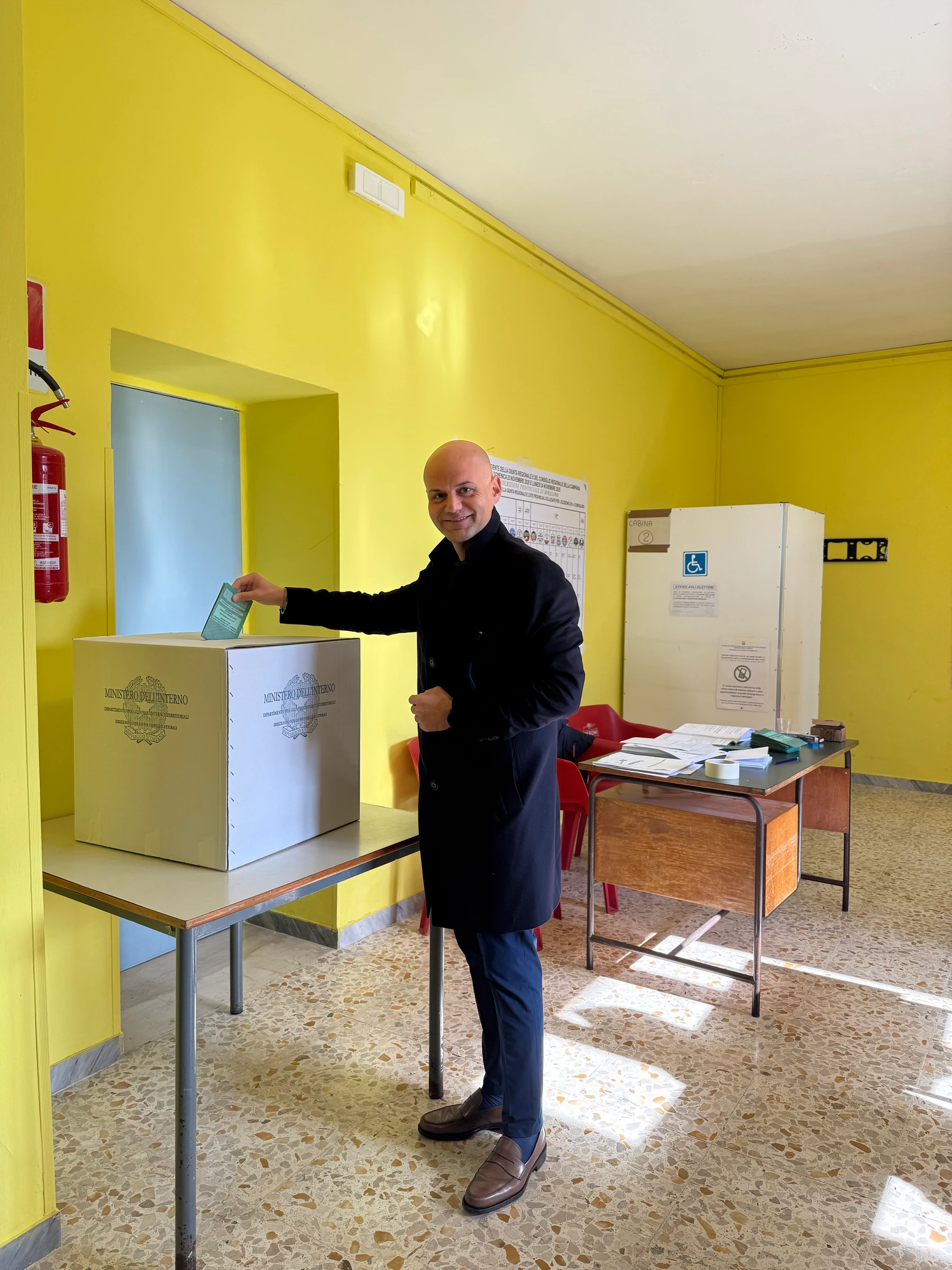 Una persona accanto a un’urna all’interno di un seggio elettorale. Archivio fotografico Regionali 2025.