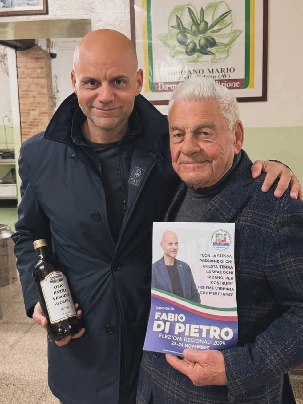 Due partecipanti posano per una fotografia con un volantino elettorale. Archivio fotografico Regionali 2025.