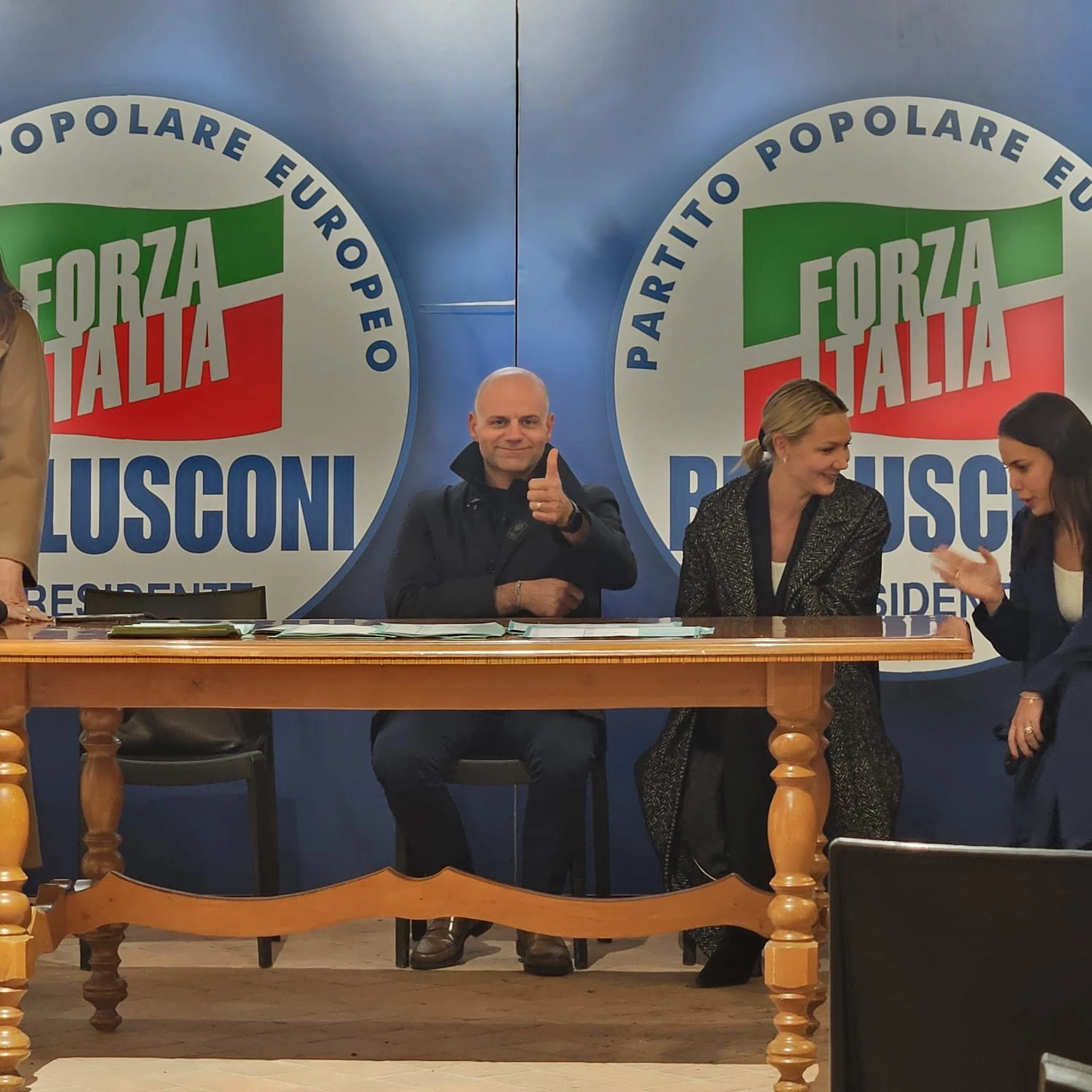 Tre partecipanti al tavolo di un incontro, davanti ai pannelli di Forza Italia. Archivio fotografico Regionali 2025.