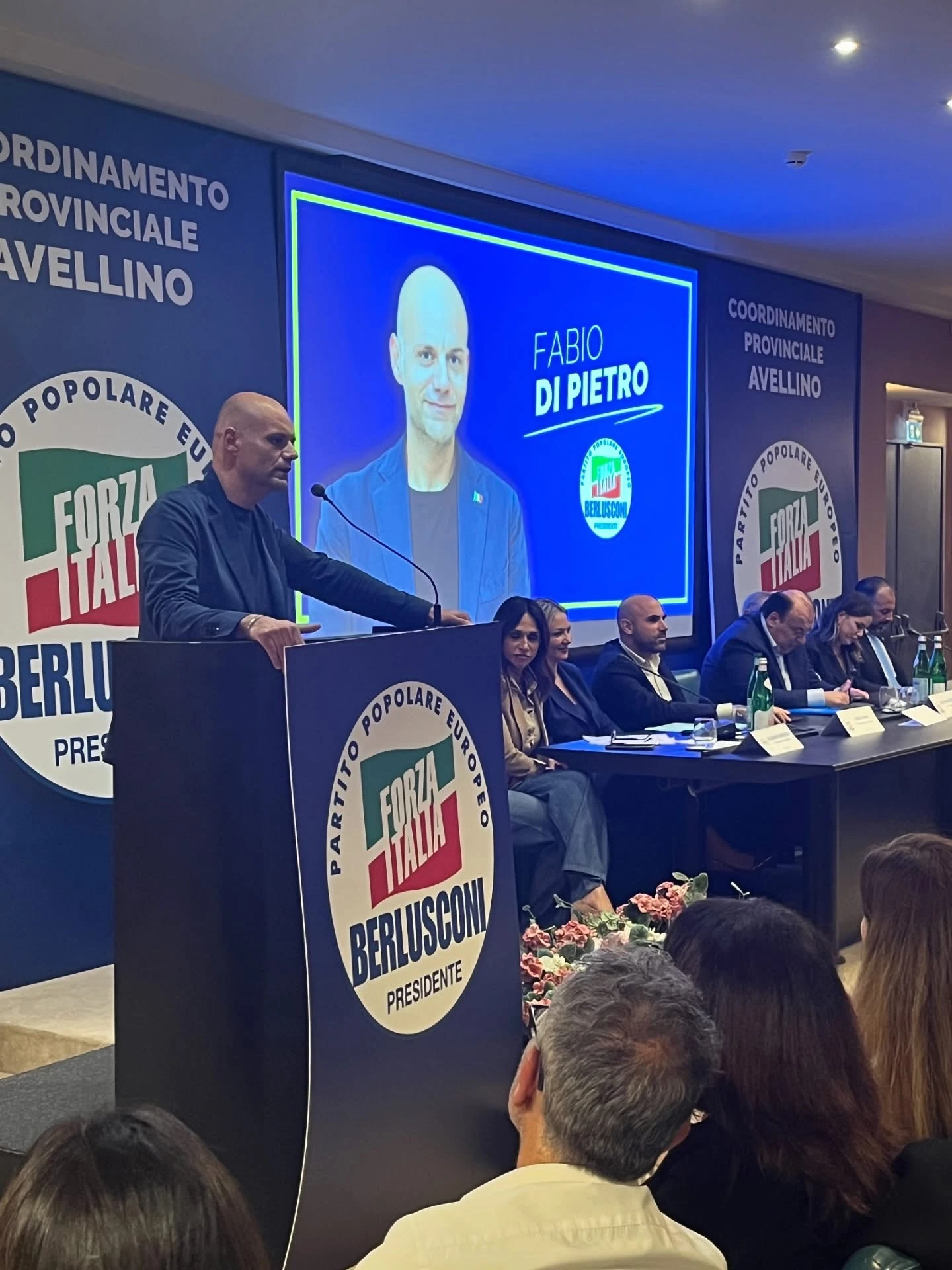 Un relatore al microfono davanti al pubblico, con il tavolo degli interventi sul palco. Archivio fotografico Regionali 2025.