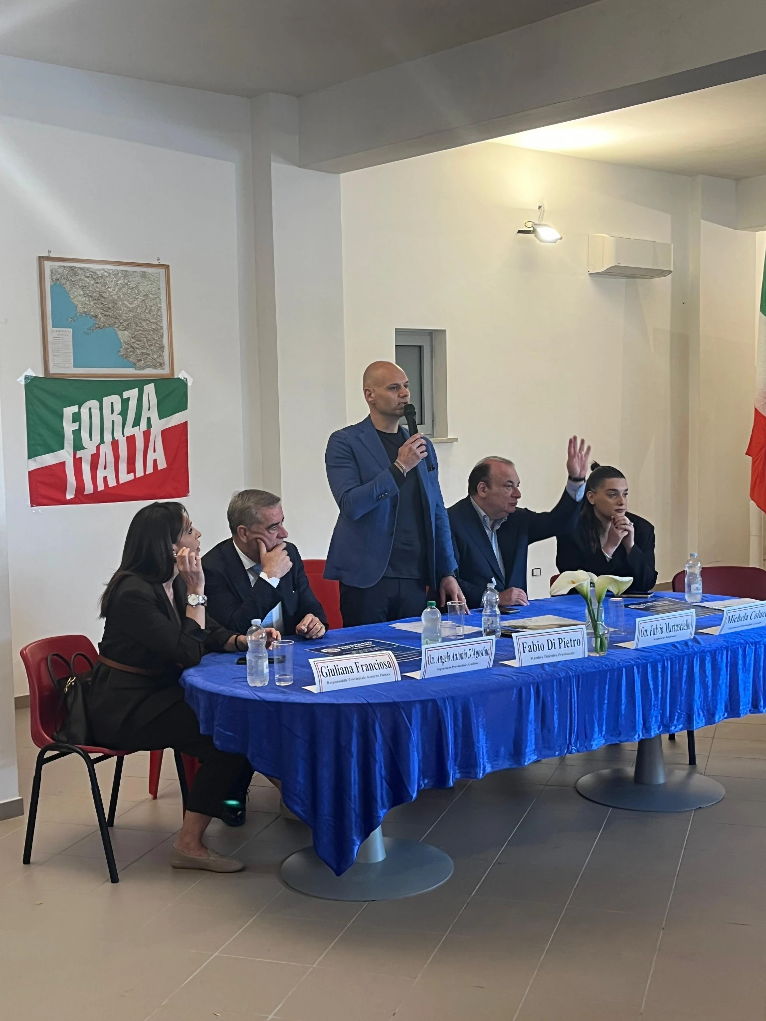 Un relatore in piedi interviene al microfono dietro il tavolo congressuale di Venticano